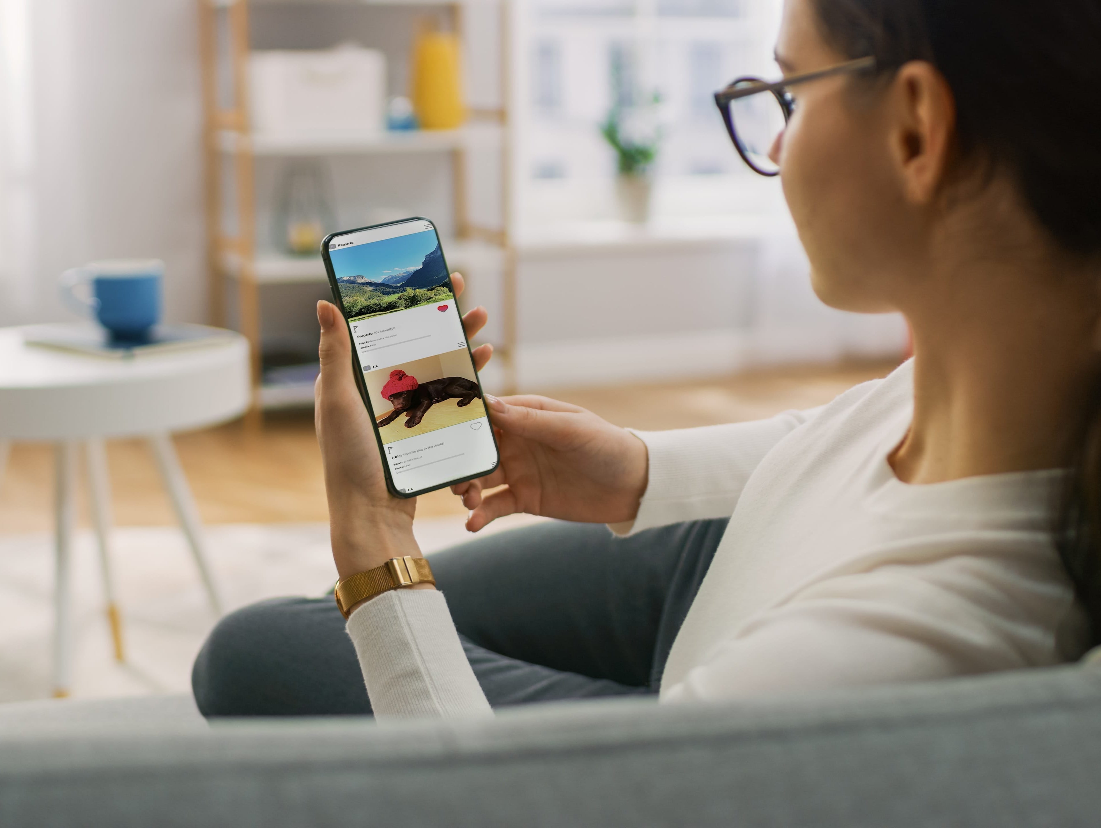 Woman enjoying casual social media browsing on a smartphone in a bright living room.