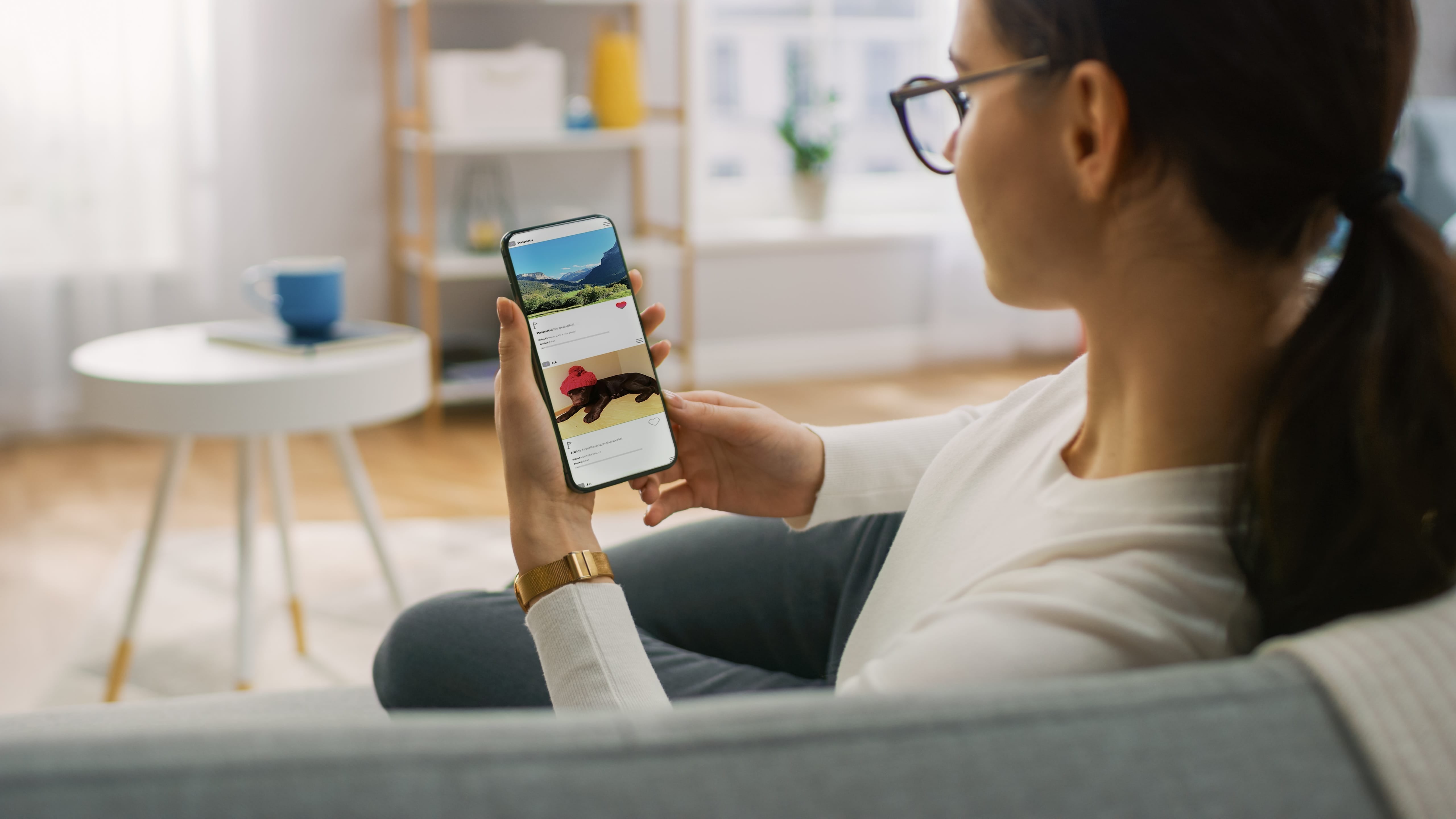 Woman enjoying casual social media browsing on a smartphone in a bright living room.
