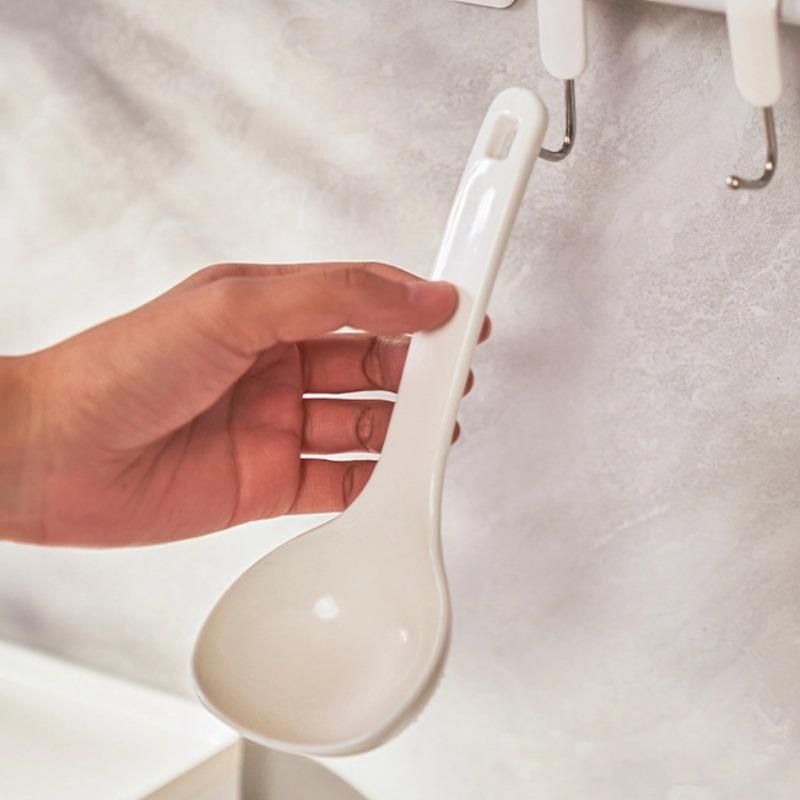 Convenient soup spoon in white, lifestyle shot showing the spoon held in hand