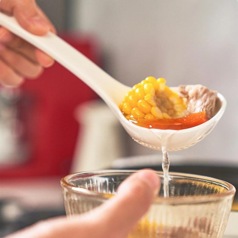 Convenient soup spoon in white, lifestyle shot showing the spoon scooping soup into a bowl