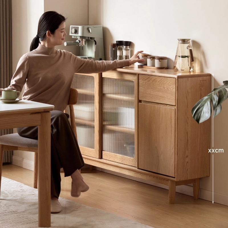 Gladys sideboard in natural oak, lifestyle shot showing a person standing at the cabinet in a styled room